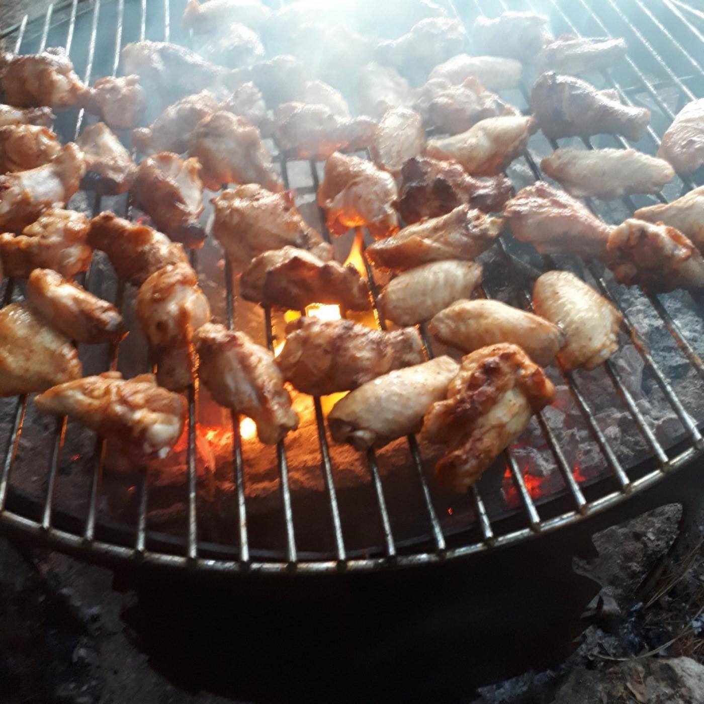 Wings cooking over a charcoal grill