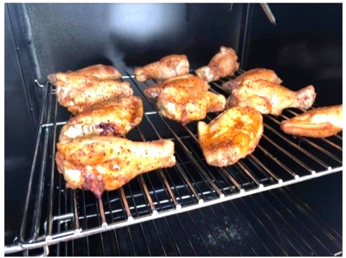 Chicken wings smoking on a rack